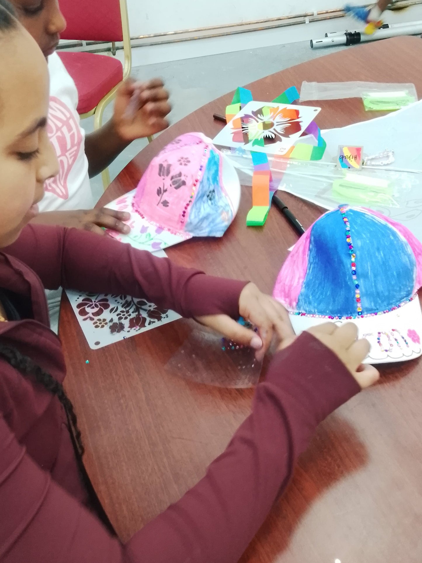 Two children sitting at a table with colorful paper crafts.