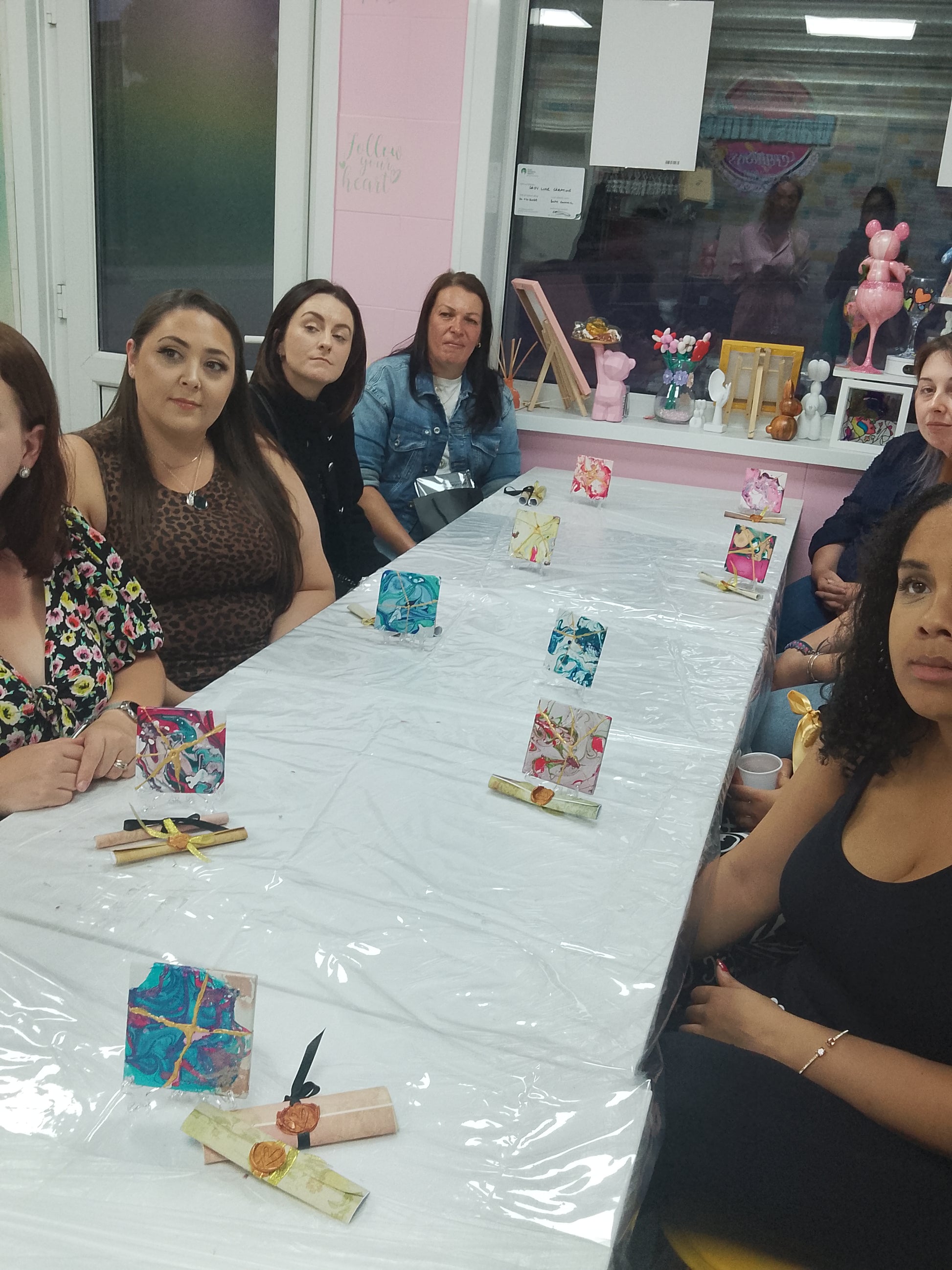 Group of women sitting around a table with decorative items on a white tablecloth.