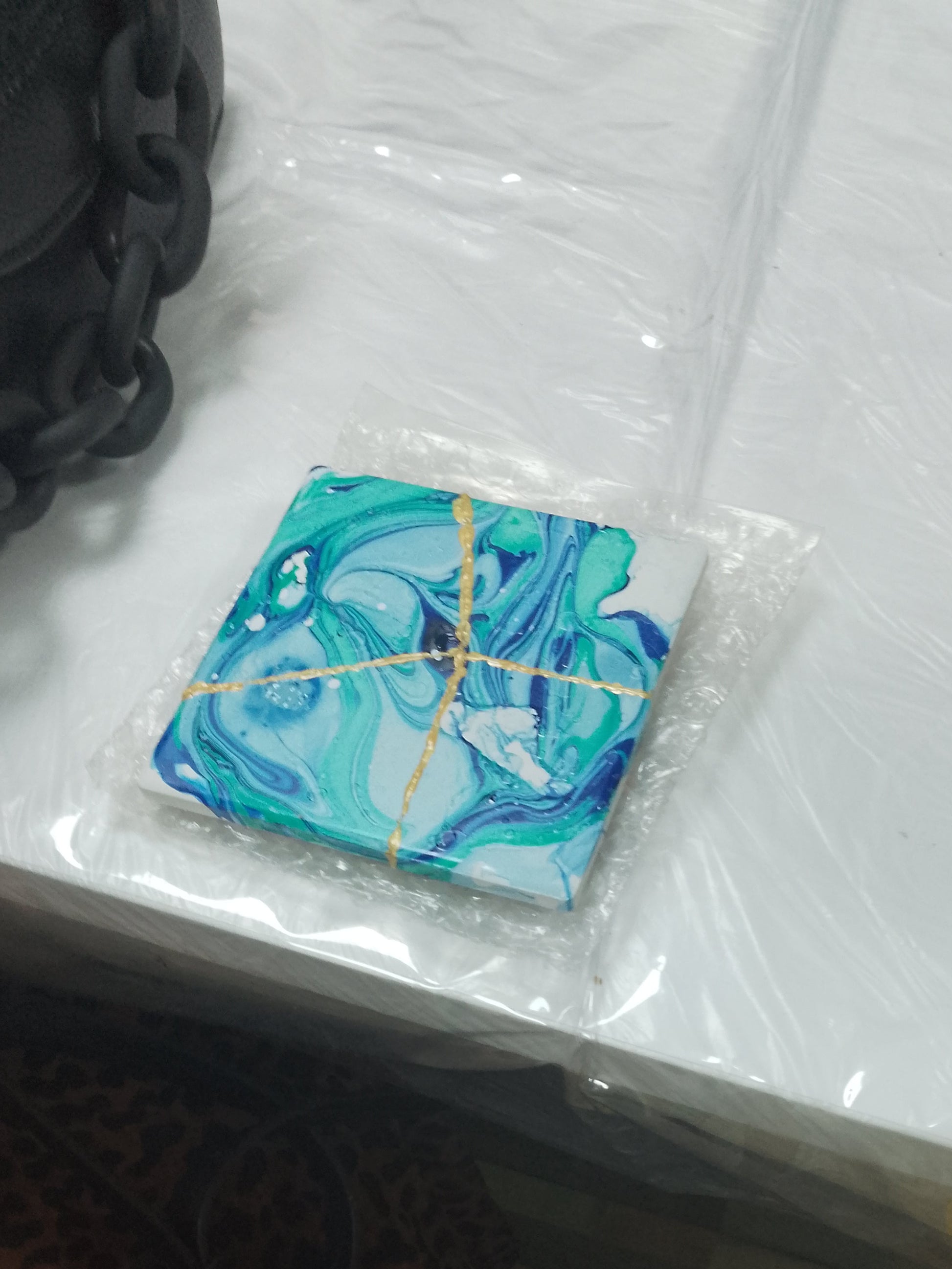 Packaged blue and green product on a white surface with leopard print fabric and yellow object in the background.